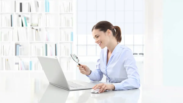 Smiling woman in office search on computer with magnifying glass — Stock Photo, Image