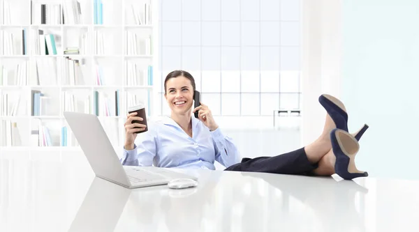 Расслабленная деловая женщина пьет кофе и разговаривает по телефону — стоковое фото