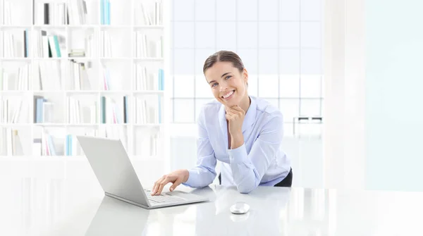 Mujer sonriente en la oficina con el ordenador en el escritorio —  Fotos de Stock