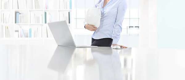 Kobieta gospodarstwa hełm Pracujesz w biurko z komputerem w biurze, pr — Zdjęcie stockowe