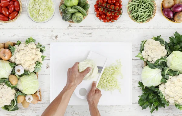 Руки приготовления пищи выше резки капусты на белой доске с — стоковое фото