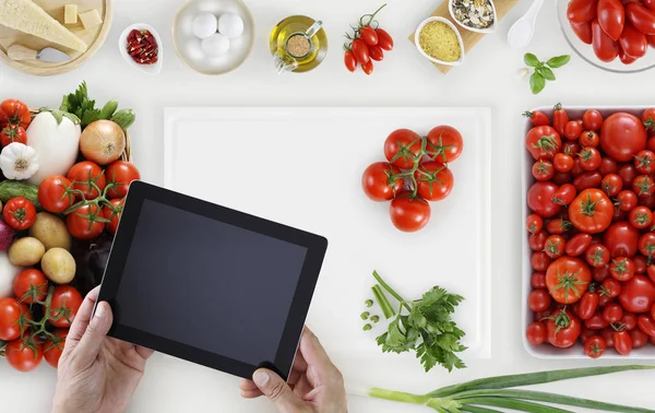 Ruce s digitálním tabletu nad na bílé prkénko s zeleninu a koše — Stock fotografie
