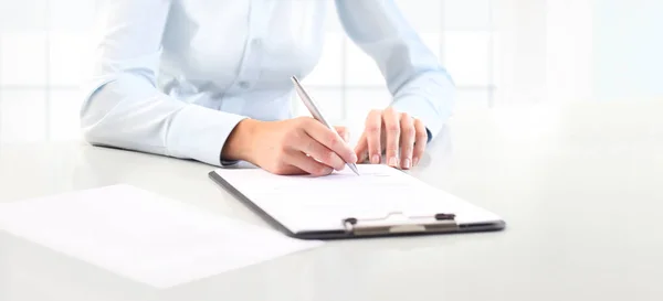 Frauenhände schreiben mit einem Stift auf ein Blatt in einem Klemmbrett, isola — Stockfoto