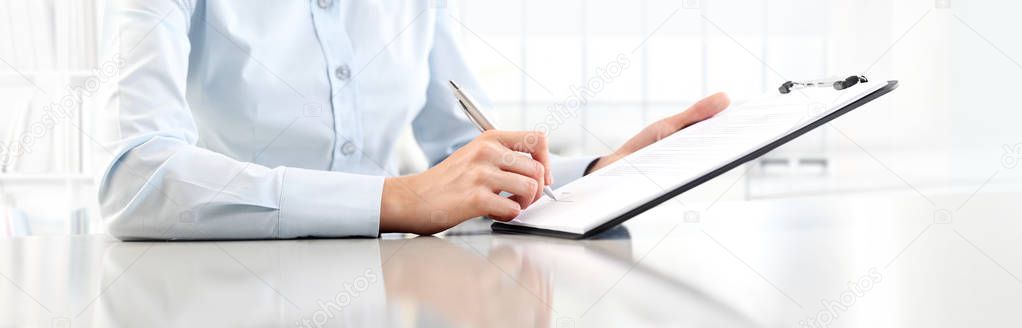 Woman's hands writing on sheet  in a clipboard with a pen, isola