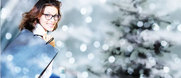 Noel alışveriş torbaları üzerinde bulanık parlak li ile gülümseyen kadın — Stok fotoğraf