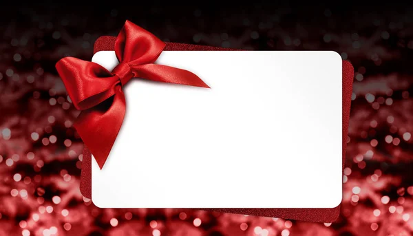 Tarjeta de regalo de Navidad con lazo rojo en luces brillantes borrosas, templ —  Fotos de Stock