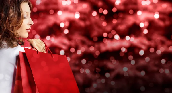 Winkelen, vrouw met tas op rode wazig felle lichten van Kerstmis — Stockfoto