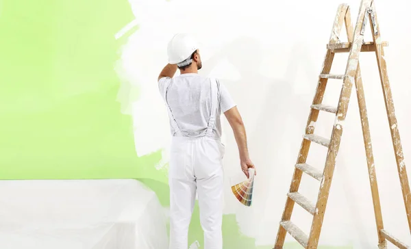 Pintor hombre en el trabajo con muestras de muestras de muestras de color, pintura de pared g —  Fotos de Stock