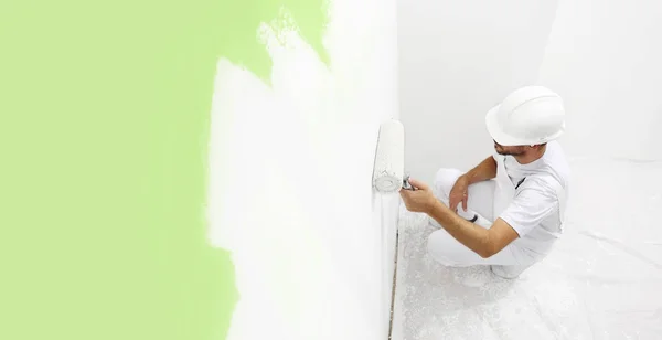 Pintor homem no trabalho com um rolo de pintura, pintura de parede col verde — Fotografia de Stock