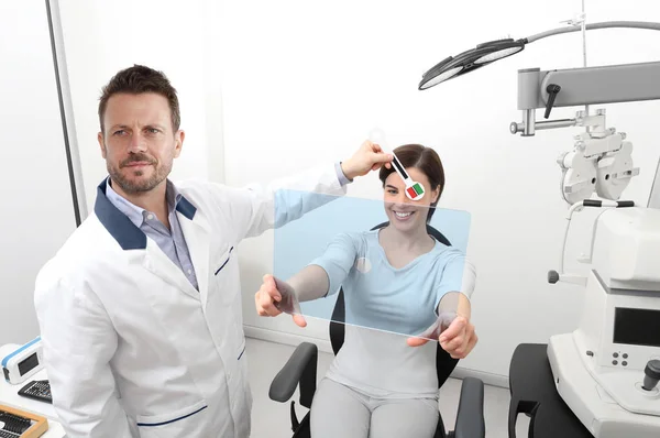 Optiker undersöker syn, kvinnlig patient pekar på den ho — Stockfoto