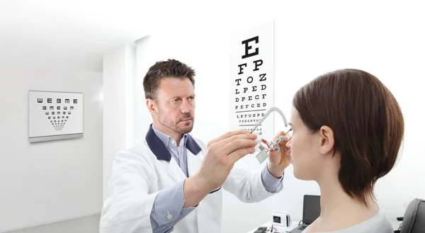 Optometrista com quadro experimental examinando a visão mulher paciente i — Fotografia de Stock