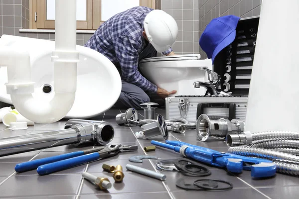 Fontanero en el trabajo en un cuarto de baño, servicio de reparación de plomería, montar — Foto de Stock