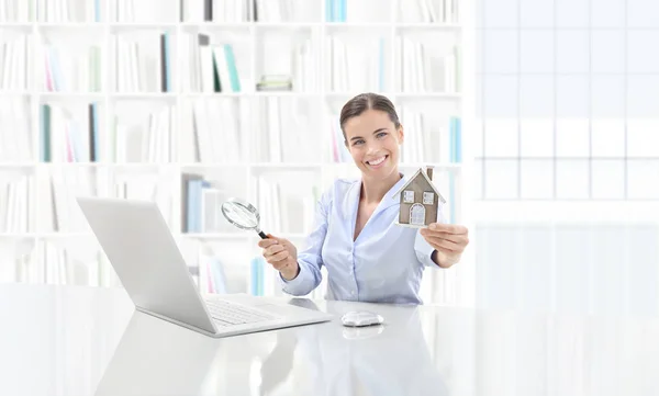 Офис недвижимости, улыбающаяся женщина агент работает на компьютере с — стоковое фото