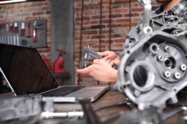 Eller kalibre ile çalışır, motor dişlilerini ölçer, ders çalışır.