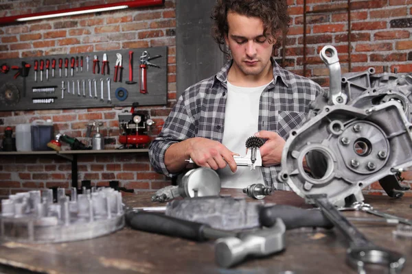 Trabajo del hombre con pinza medir el engranaje del motor, reparación y limpieza — Foto de Stock