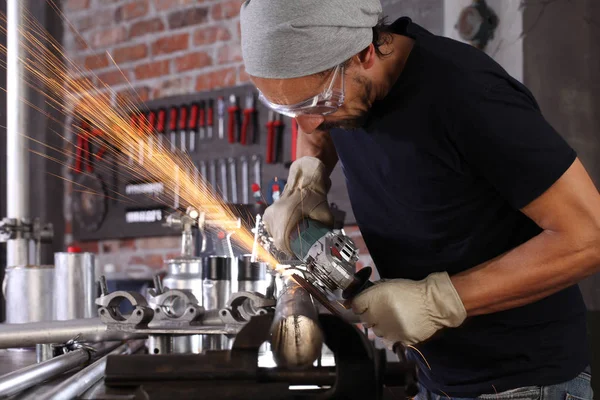 Man werk in huis werkplaats garage met haakse slijper, bril en — Stockfoto