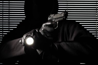 Hırsızlık ve soygun. usta profesyonel maskeli hırsız bir silah ve meşale tutan ve eve kırma, el siyah pencere arka plan üzerinde yakın