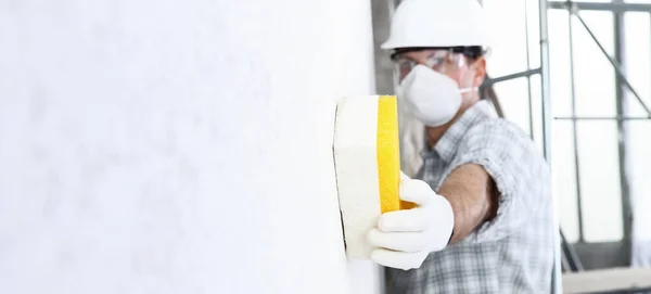 建筑工人使用海绵在墙上专业建筑工人与面具 安全帽 手套和防护眼镜 室内建筑工地 复制空间背景 — 图库照片