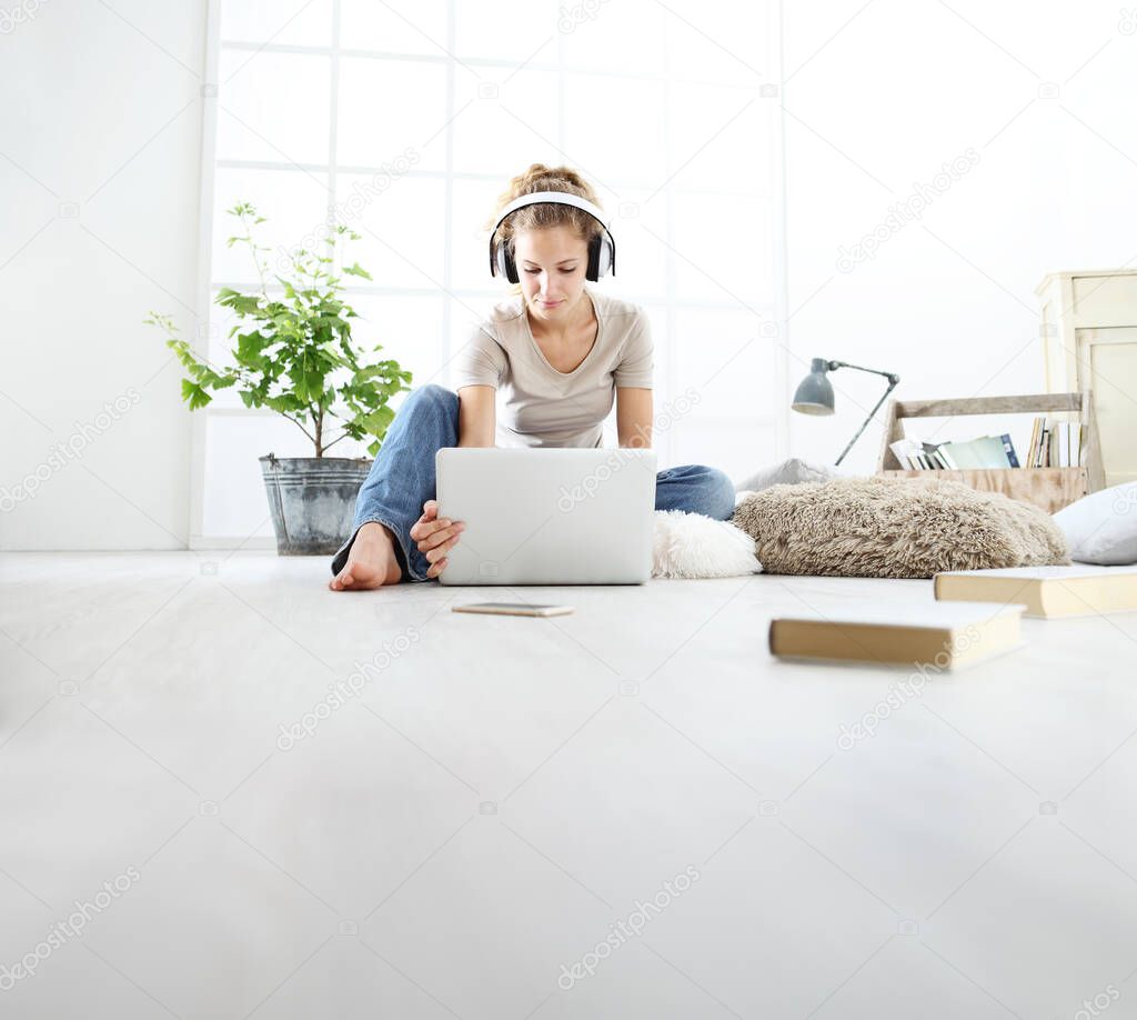young woman sitting in living room studying with headphones and computer, stay at home concept