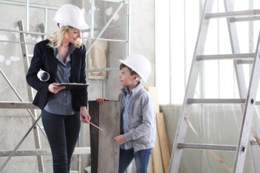 woman interior designer or architect mom with her son at work, they choose how to furnish the house, inside the construction site clipart