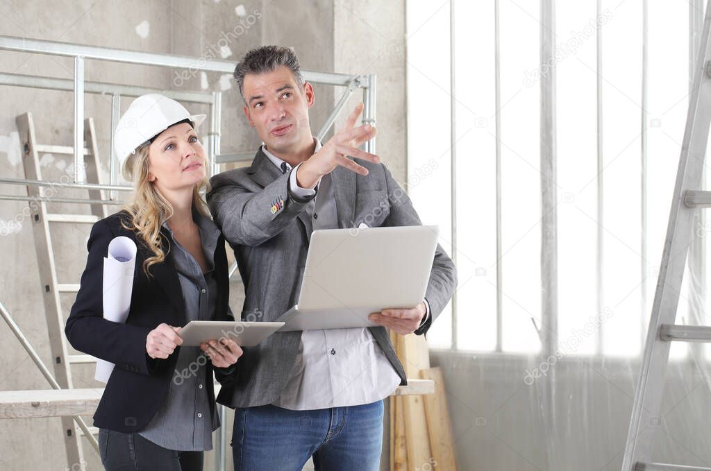 man and woman architects or engineers with computer work together in the inside the construction building site