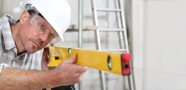 construction man worker measure with level laser wear hard hat and protective glasses  at interior building site