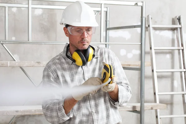建筑工地工人测量仪器 带着带硬礼帽 眼镜和听觉保护耳机 — 图库照片