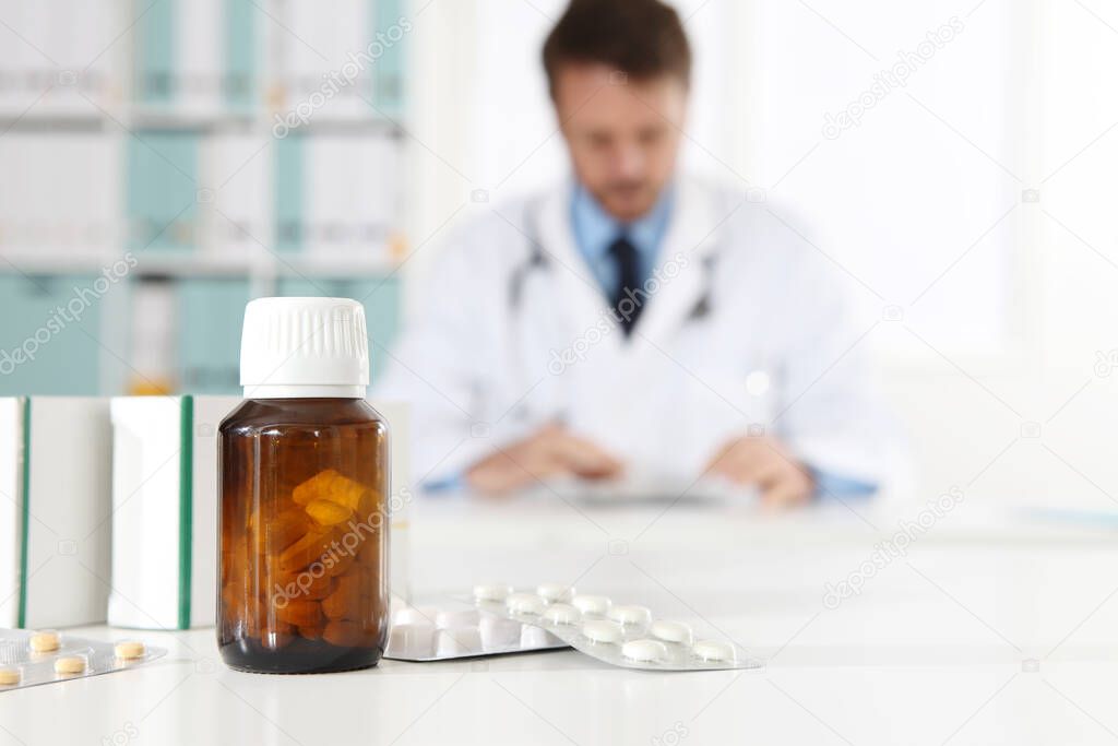pills, blister, bottle and tablets boxes medicine on medical desk office with doctor on background