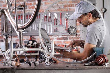 Adam bilgisayardaki antika bisikleti tamir ediyor yedek parçaları arıyor ve garajdaki atölyede aletlerle interneti görüyor.