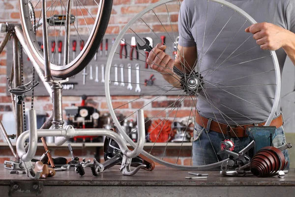 人在工作台上的车库里用工具修理老式自行车 这个概念很模糊 — 图库照片