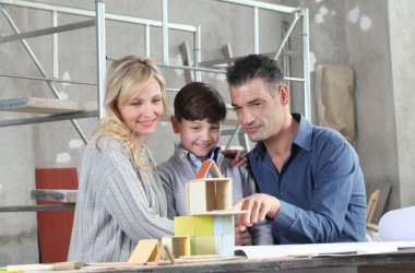 Mutlu çocuklar ve ailesi iç mekanda inşaat modelleriyle bir ev inşa etme oyunu oynuyorlar. Ev satın alma ve bina hedefi kavramı