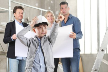 Ev dekorasyonu ve ev dekorasyonu hakkında konuşmak için iç inşaat sahasında toplanan ve çocuk tarafından ev yapımı hedef konsepti olarak gösterilen bir aileye ev tasarımı planları gösteren mimar