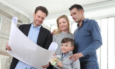 Mimar, çocuklu bir aileye ev tasarımı planlarını gösteriyor. Ev görünümü, iç dekorasyon, ev düzeni ve duvar renkleri hakkında konuşmak için iç inşaat sahasında toplantı.