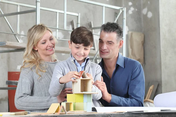 Mutlu çocuklar ve ailesi iç mekanda inşaat modelleriyle bir ev inşa etme oyunu oynuyorlar. Ev satın alma ve bina hedefi kavramı