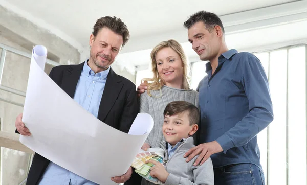 Mimar, çocuklu bir aileye ev tasarımı planlarını gösteriyor. Ev görünümü, iç dekorasyon, ev düzeni ve duvar renkleri hakkında konuşmak için iç inşaat sahasında toplantı.