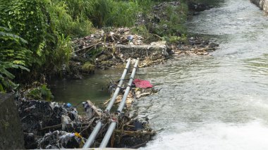 Plastik çöplerle dolu bir nehir kıyısı. Geri dönüştürülemez ve çevreyi kirletemez.