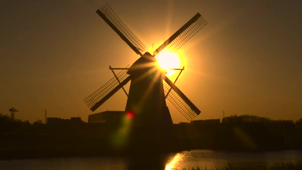 Traditionelle Windmühle am Ufer des Flusses bei Sonnenuntergang — Stockvideo