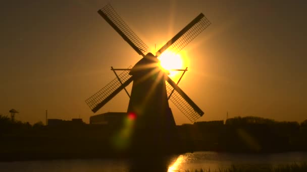 Molino de viento tradicional en la orilla del río al atardecer — Vídeo de stock