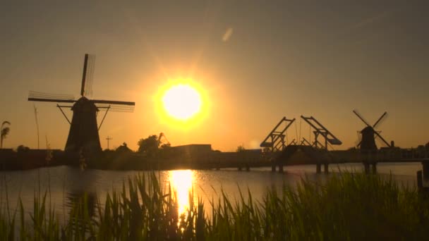 Molinos de viento tradicionales en la orilla del río al atardecer — Vídeo de stock