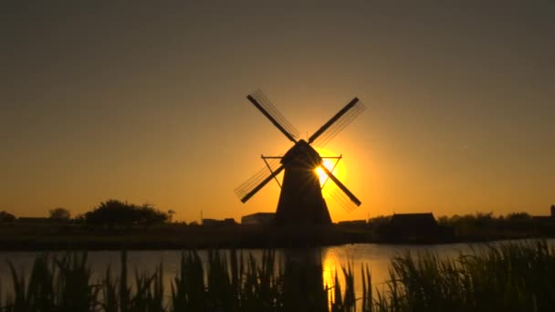 Traditionell väderkvarn på flodstranden vid solnedgången — Stockvideo