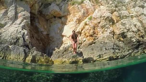 MOCIÓN LENTA: Chica salta de cabeza en el refrescante océano y nada bajo la cámara — Vídeos de Stock