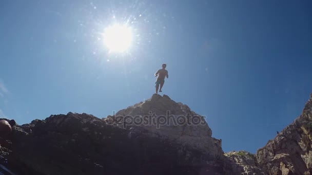 Αργή κίνηση εσωτερικη υποβρύχιο: Άνθρωπος πηδάς από ένα βράχο υψηλής Ωκεανό στο νερό — Αρχείο Βίντεο