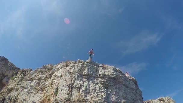 SLOW MOTION UNDERWATER: Cheerful man hands raised jumping off a high ocean cliff — Stock Video