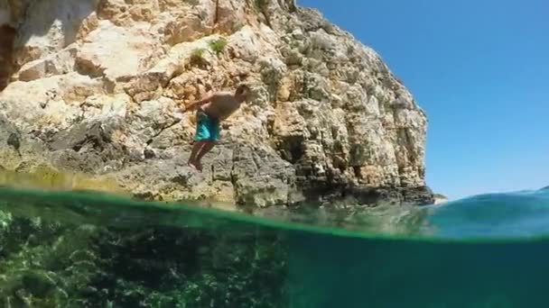 MOCIÓN LENTA: Hombre saltando de cabeza en el refrescante océano y nada bajo el agua — Vídeos de Stock