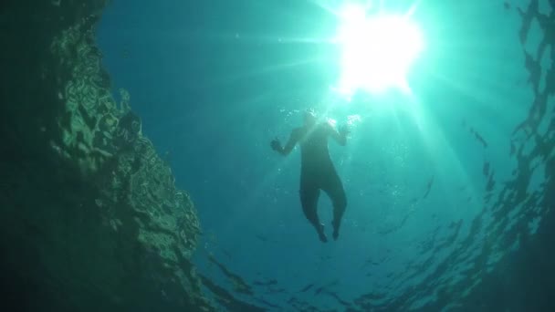 SLOW MOTION UNDERWATER: Young man swimming below the water surface in ocean — Stock Video