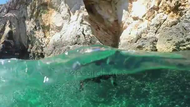 Zwolnionym tempie, pod wodą: Ładna miniatura pinscher pływanie na skalistym wybrzeżu — Wideo stockowe