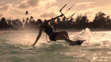 Ağır çekim kadar yakın: Mutlu uçurtma kız kiteboarding gülümseyen ve su
