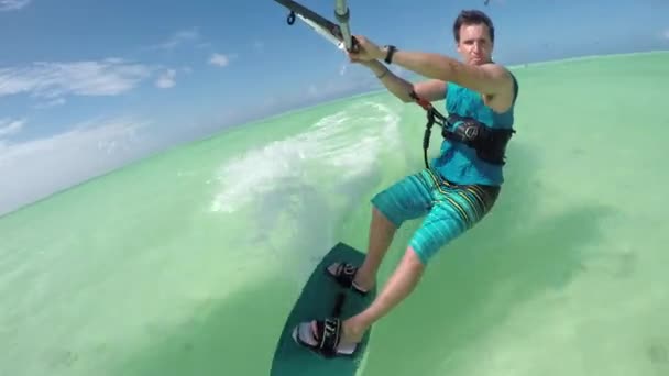 Close-up: Happy jonge kiter sportman kiteboarding op perfecte turquoise zee — Stockvideo