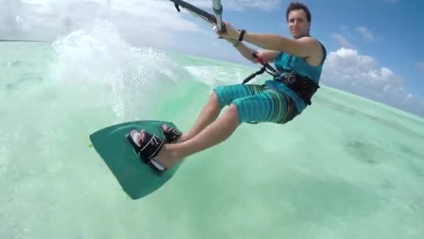 Close-up: Vrolijke jonge kiter sportman kiteboarding op perfecte turquoise zee — Stockvideo