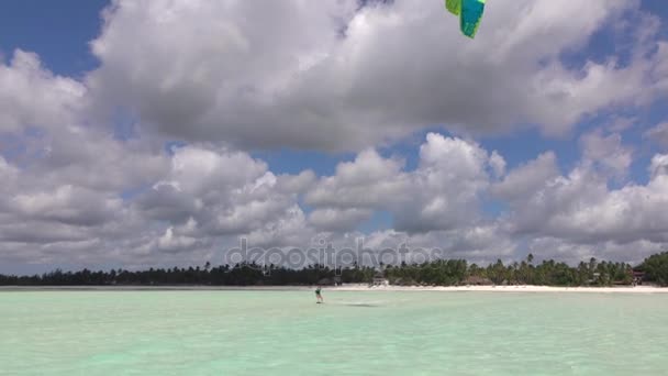 Kvinna kiteboarder skärmflygning i perfekt blå lagunen framför exotiska sandstranden — Stockvideo